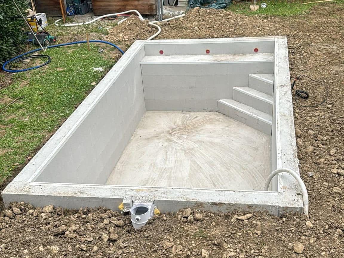 Bassin brut 6×3 m avant pose du liner : escalier d’angle, banquette et skimmer en place