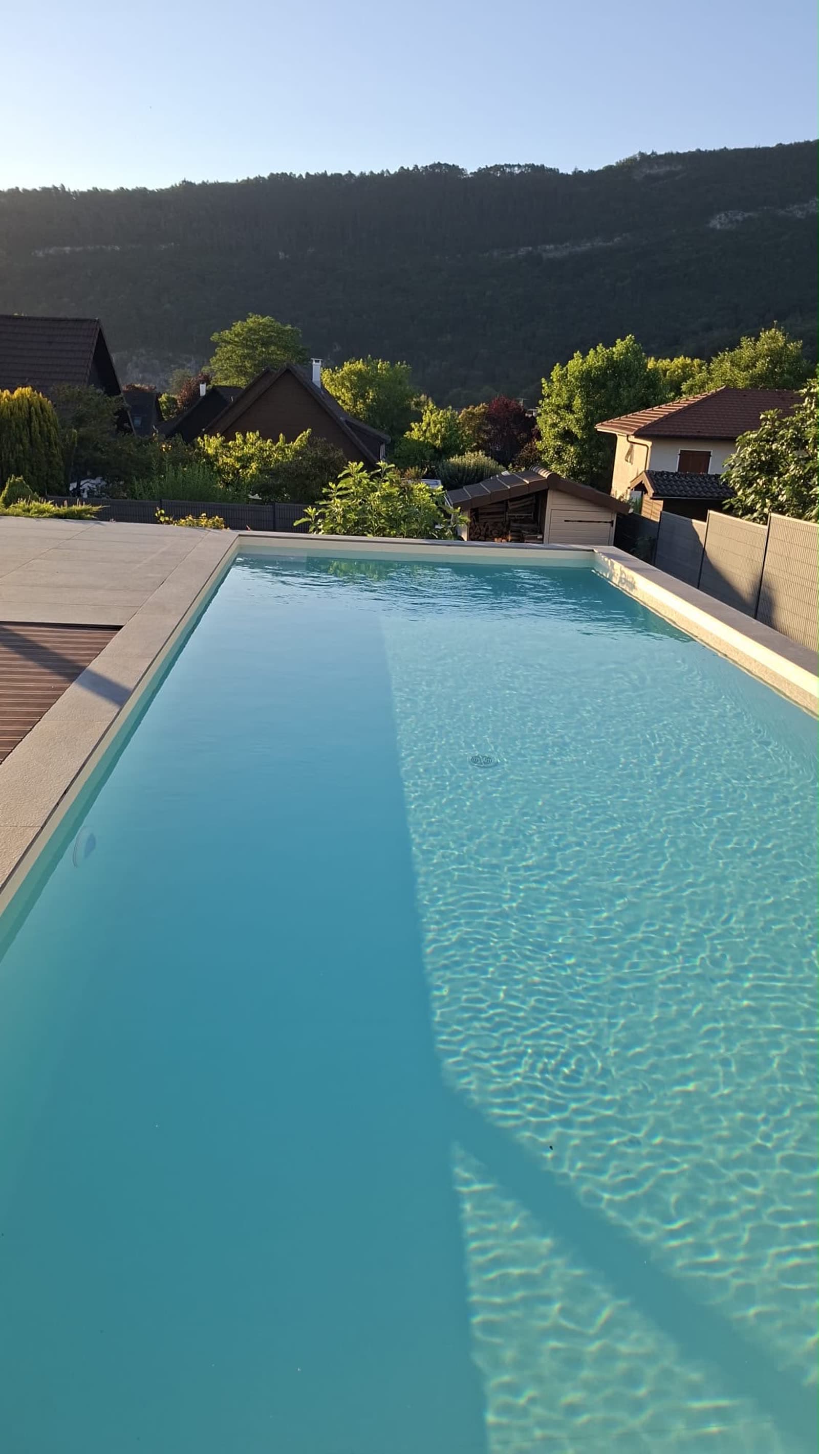 Piscine 11×4 m à Genève avec liner armé sable, eau lagon au soleil couchant face aux reliefs