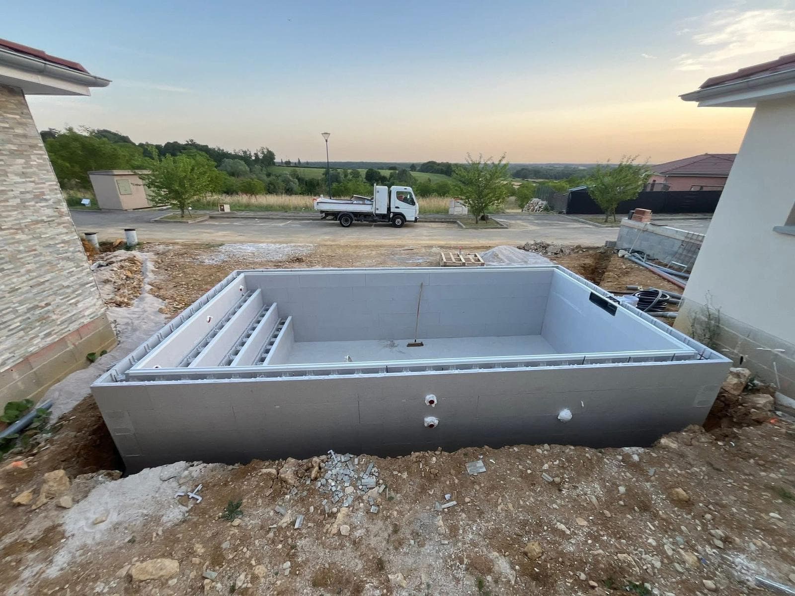 Structure du bassin 7×3 m en blocs coffrants, escalier pleine largeur, au coucher du soleil
