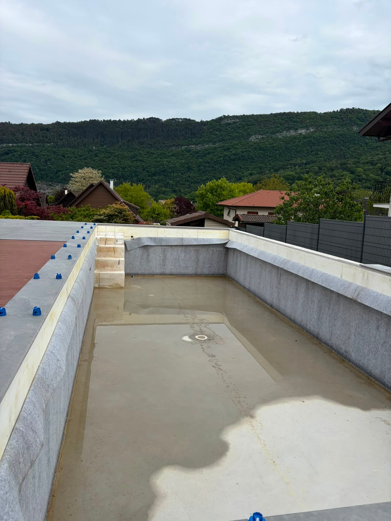 Avant la pose : bassin nu sous feutre de protection, margelles et terrasse en cours d’aménagement