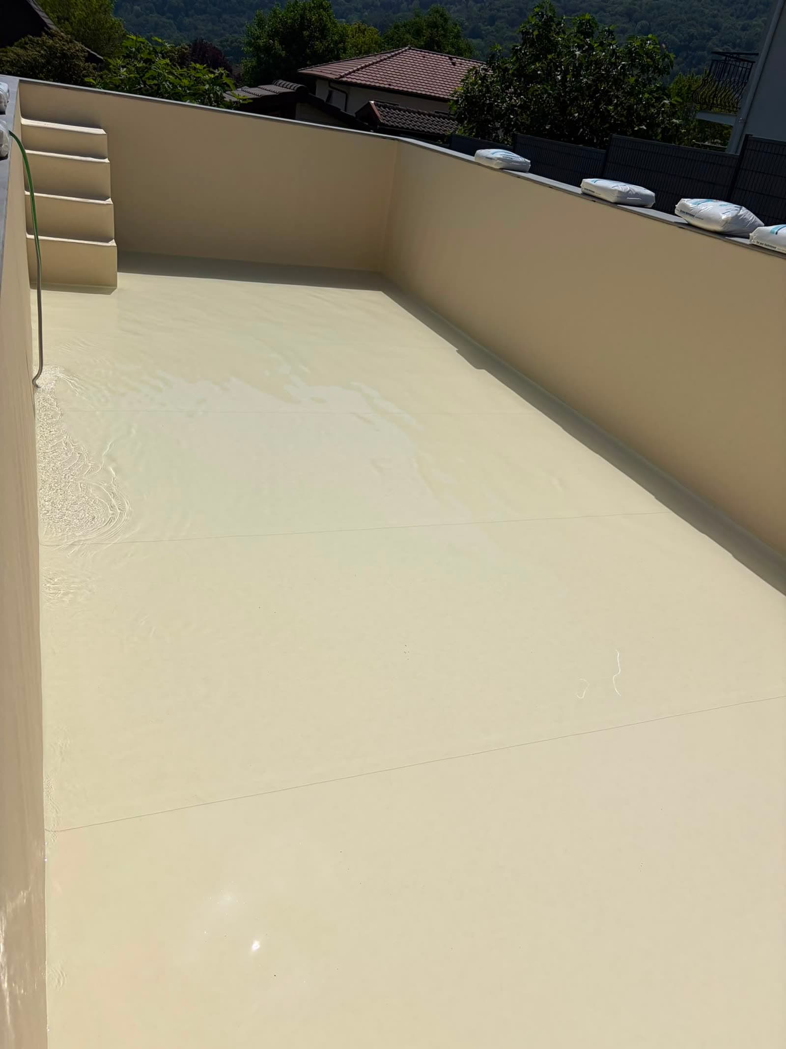 Mise en eau du liner armé sable fraîchement soudé, escalier d’angle droit au fond du bassin